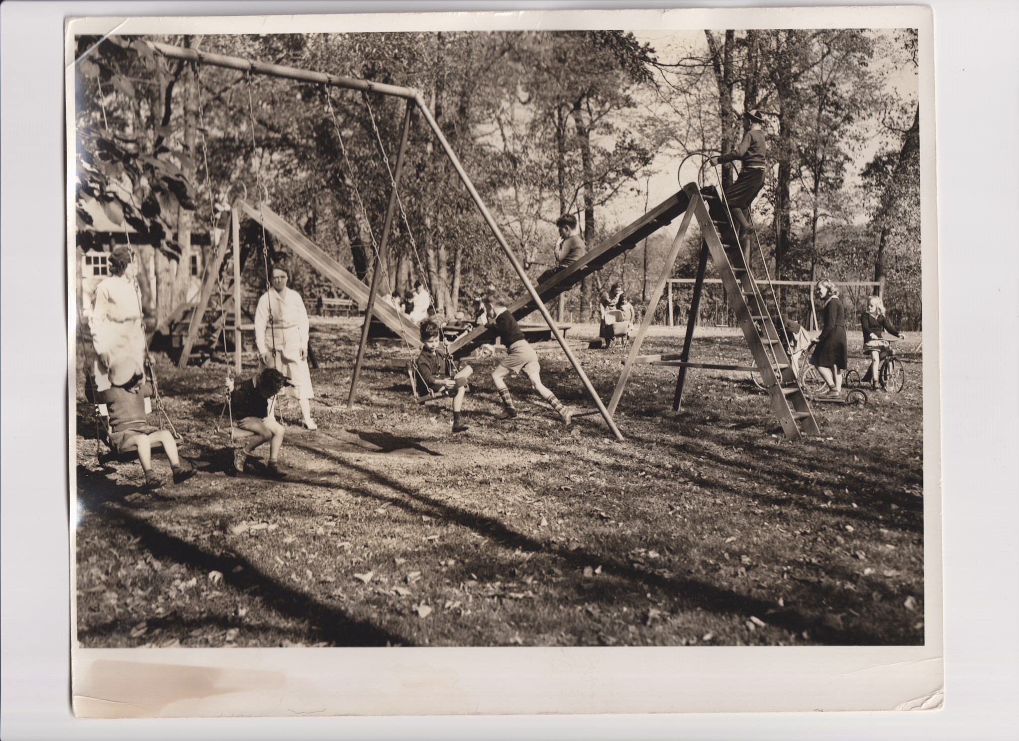 A black-and-white photograph of the Bancroft School, depicting students at play on a swing set outdoors.