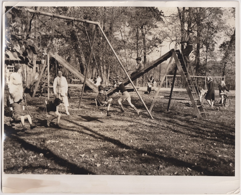 A black-and-white photograph of Bancroft School students on a playground, accompanied by staff members.